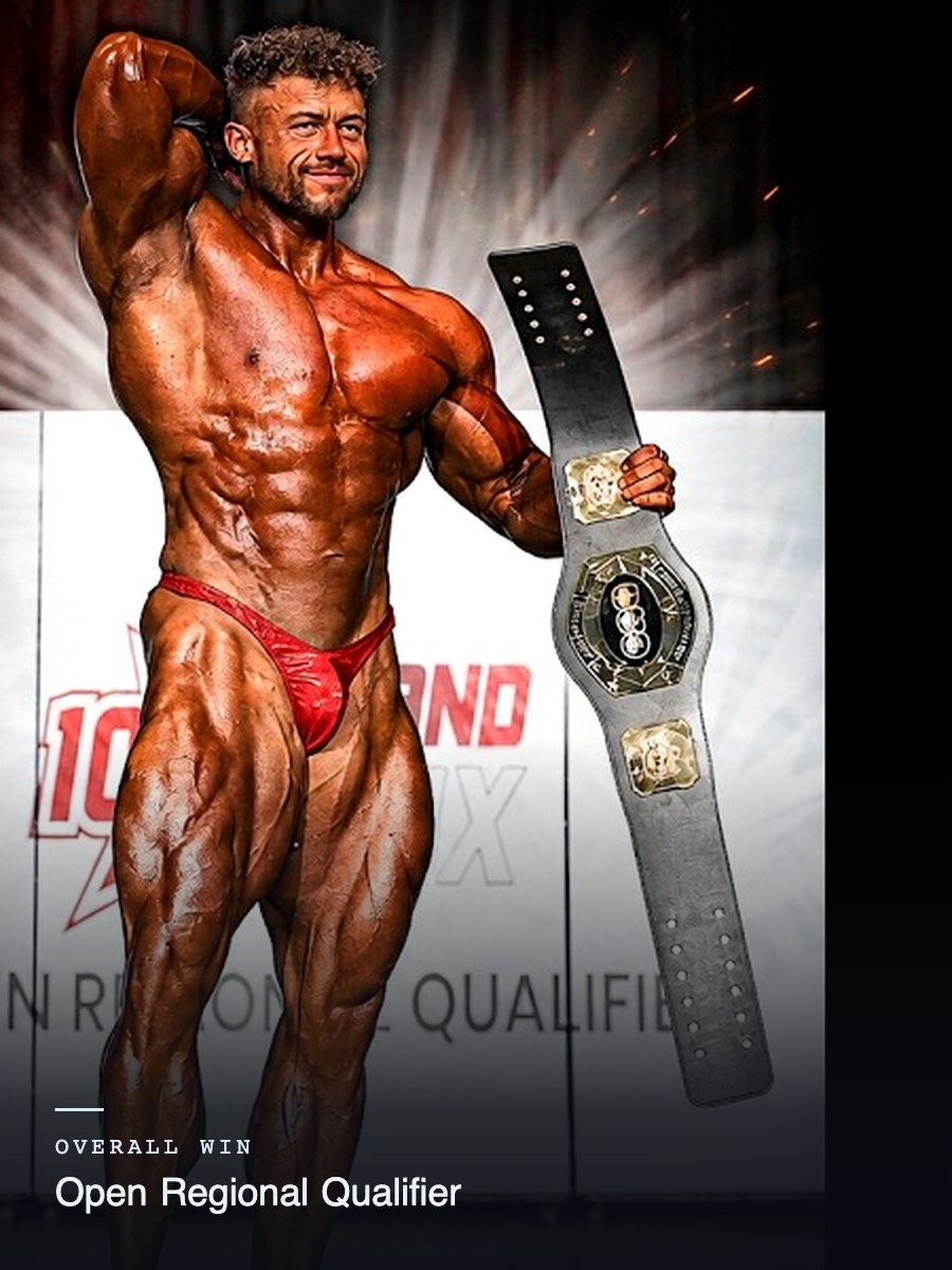 Reece Pearson on stage holding a championship belt at an Open Regional Qualifier, 1 of 4